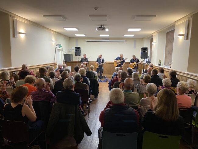 Rum Ragged on stage at Casterton Village Hall playing to a packed audience
