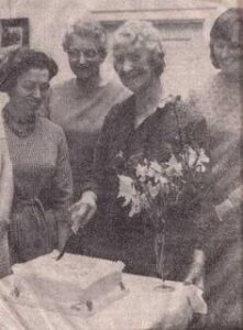 Mrs Roper cutting cake to celebrate Casterton WI's Golden Jubilee