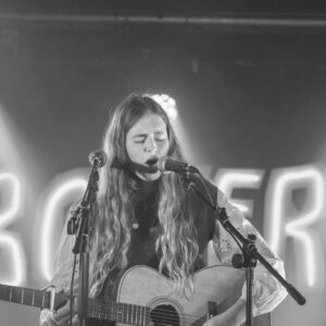 Anouska Assisi playing guitar and singing